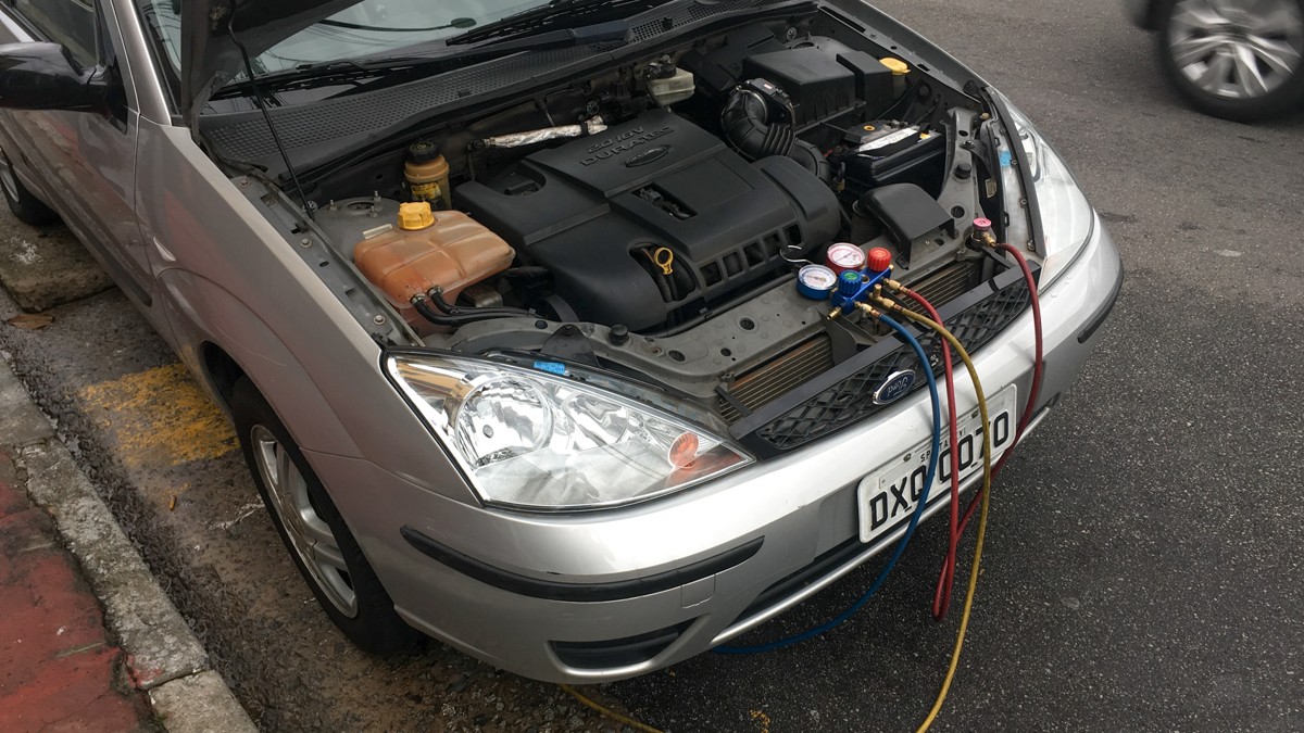 Stock photo: refrigerant manifold gauges and service hoses connected to a Ford Focus with its hood open.