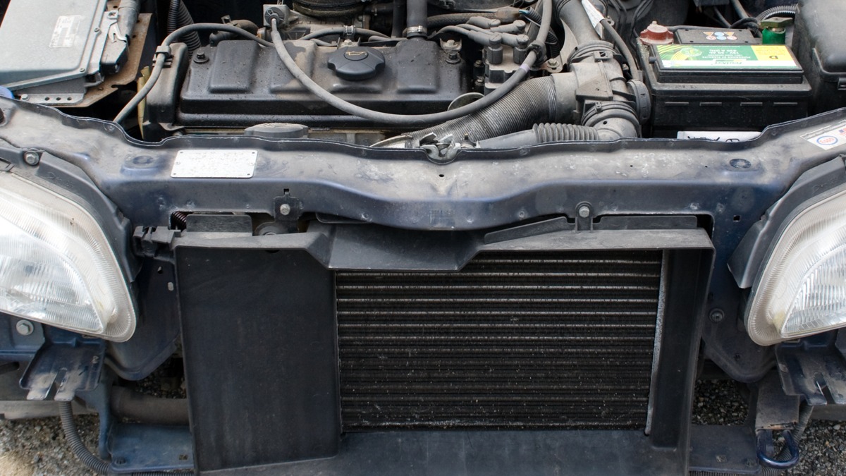 Stock photo: exposed radiator and cooling hoses at the front of a vehicle with its hood open.