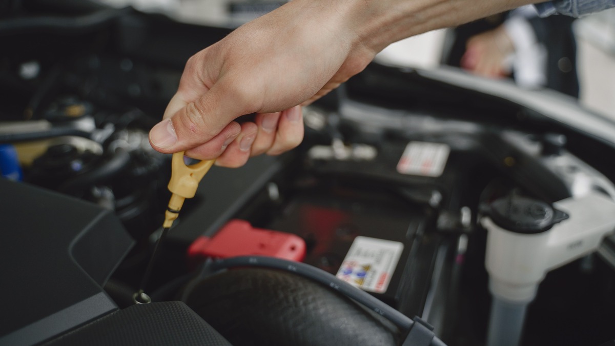 Stock photo: Hand checking engine oil using a yellow dipstick in an open engine bay.