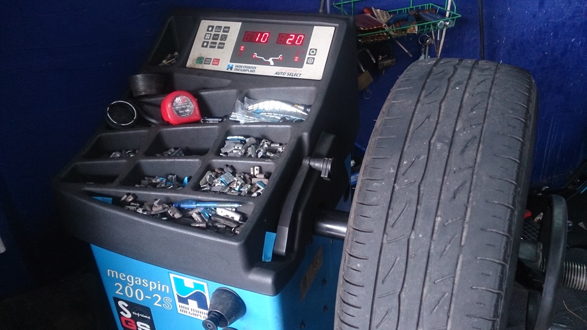 Stock photo: Tire mounted on a wheel balancing machine with digital readings and wheel weights visible.