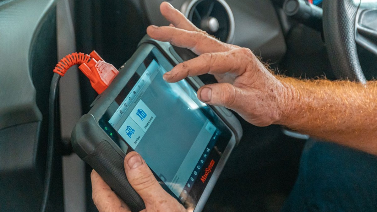 Stock photo: hands operating a diagnostic scanner with a red cable attached inside a car.