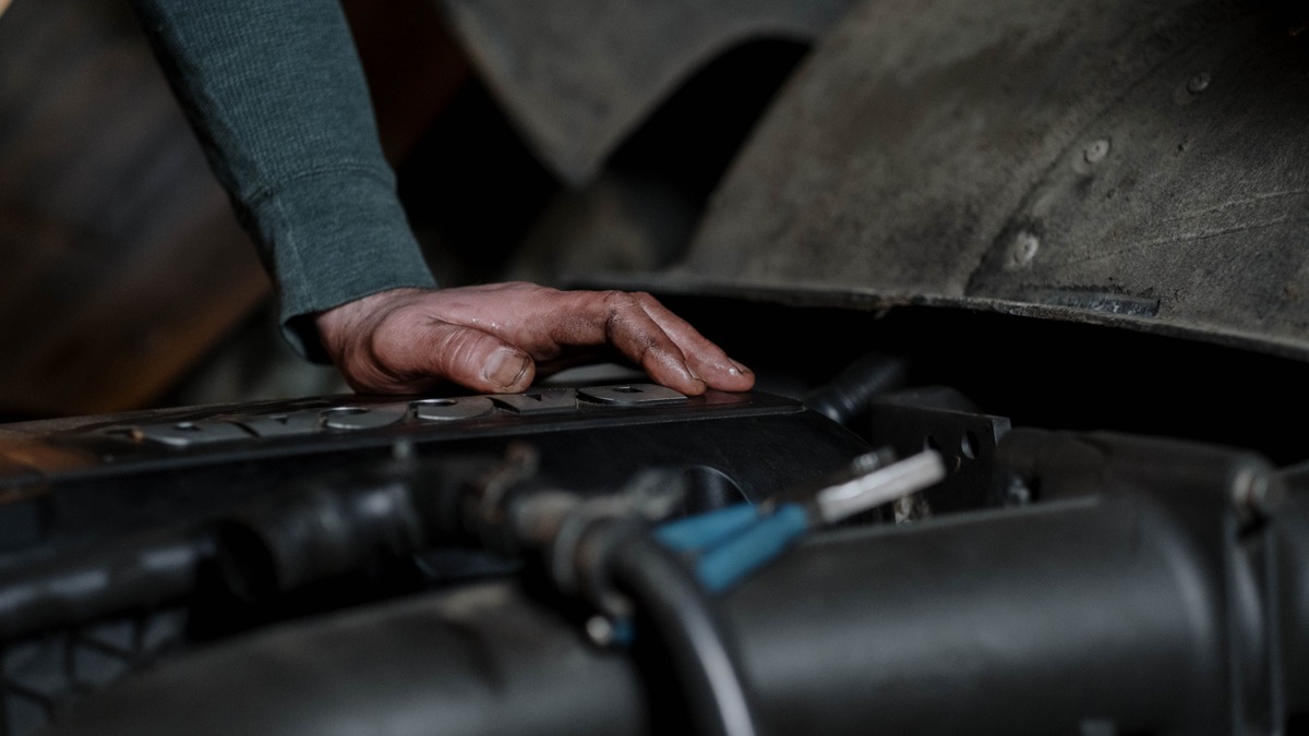 Stock photo: Close-up of a hand inspecting components beneath an open vehicle hood.